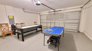 Un tavolo da ping pong in un garage, con un altro tavolo da tennis e sedie.
