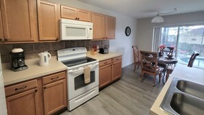 Una cocina con armarios de madera, una estufa blanca, un microondas y un lavamanos.