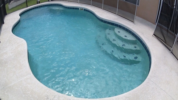 Una piscina de borde curvo y bordeado con azulejos.