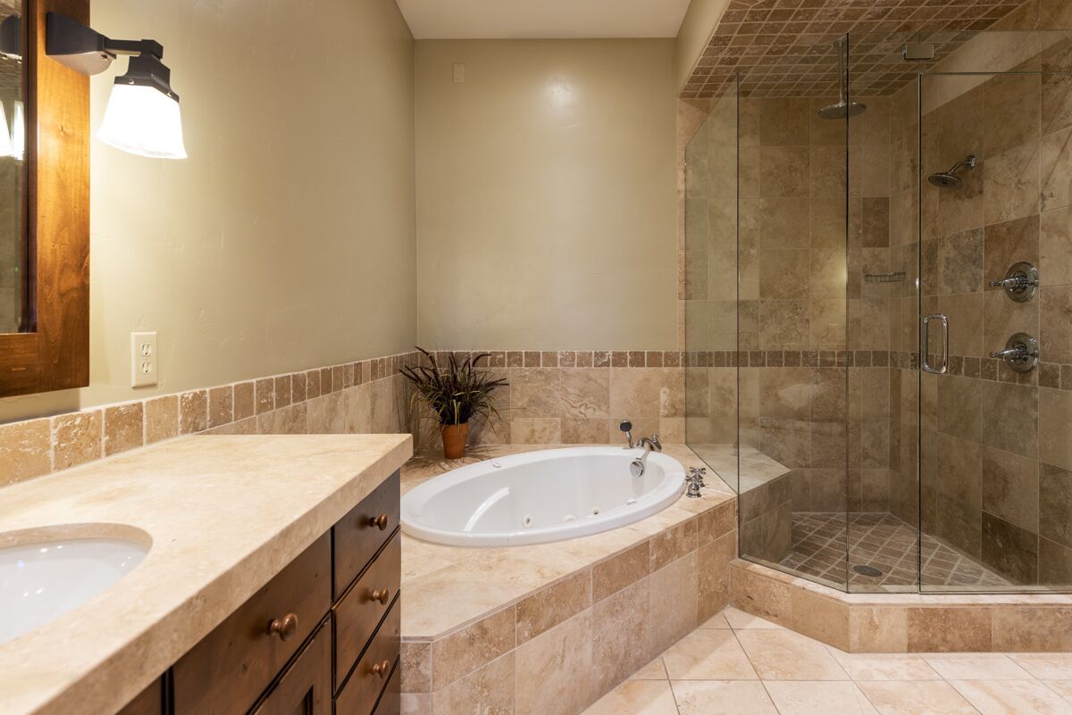 A bathroom with a double sink, a large bathtub, and a glass-enclosed shower area.