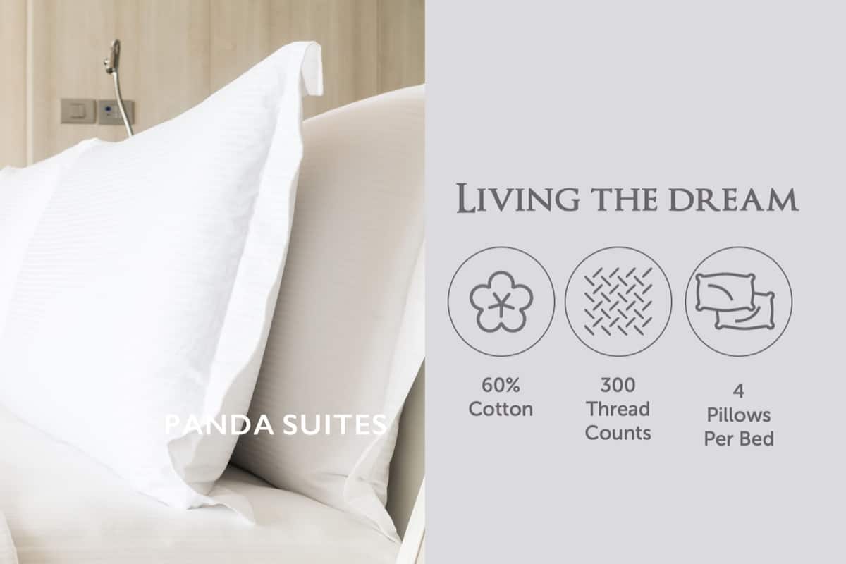Un lit avec une literie blanche et un oreiller, portant l’inscription « Panda Suites ».