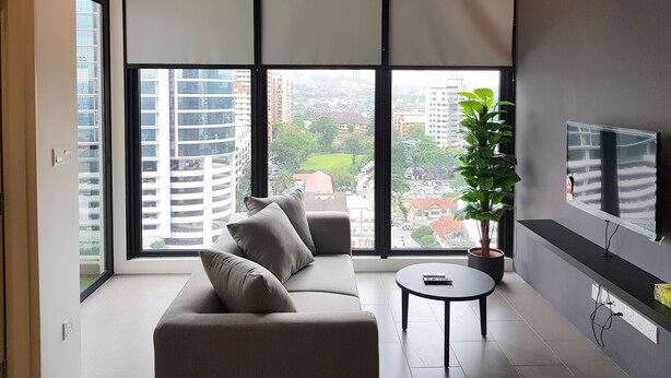 Un salon moderne avec un canapé, une petite table, une plante en pot et un téléviseur fixé au mur.