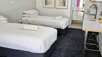 A hotel room with two beds, a kitchenette, and a small dining area.