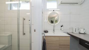 Un baño moderno con cabina de ducha de vidrio, un lavabo con espejo y un inodoro.