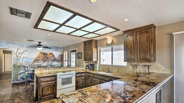 A kitchen with a large island, wooden cabinets, and a mural on the wall.