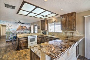 A kitchen with a large island, wooden cabinets, and a mural on the wall.