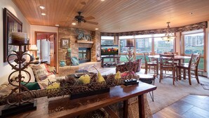 A spacious living room with a fireplace, a dining area, and large windows offering a view of the city. - CX115 | Nicely Updated Condo | Direct Access to Skiing | Views | Winter Shuttle (Steamboat Springs)