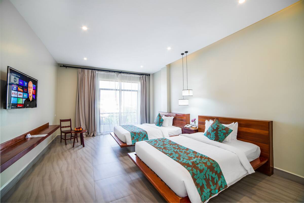 A hotel room with two beds, a TV, a desk, and a chair.