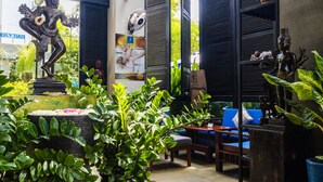A room with a statue, a fan, a poster, and a blue sofa. - Bayon Modern Residence (Siem Reap)