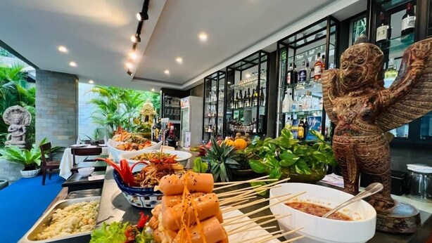A buffet with various dishes, a bar area with bottles, and a decorative elephant statue. - Bayon Modern Residence (Siem Reap)