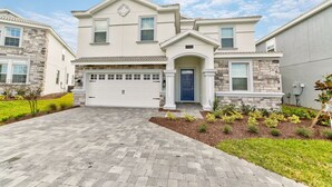 A two-story house with a garage, a stone facade, and a well-maintained lawn.