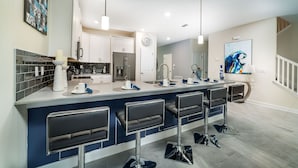 A modern kitchen with a central island, bar stools, and a large window.