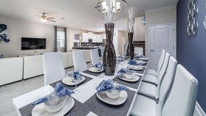 A modern dining area with a long table set for six, white chairs, and decorative vases.