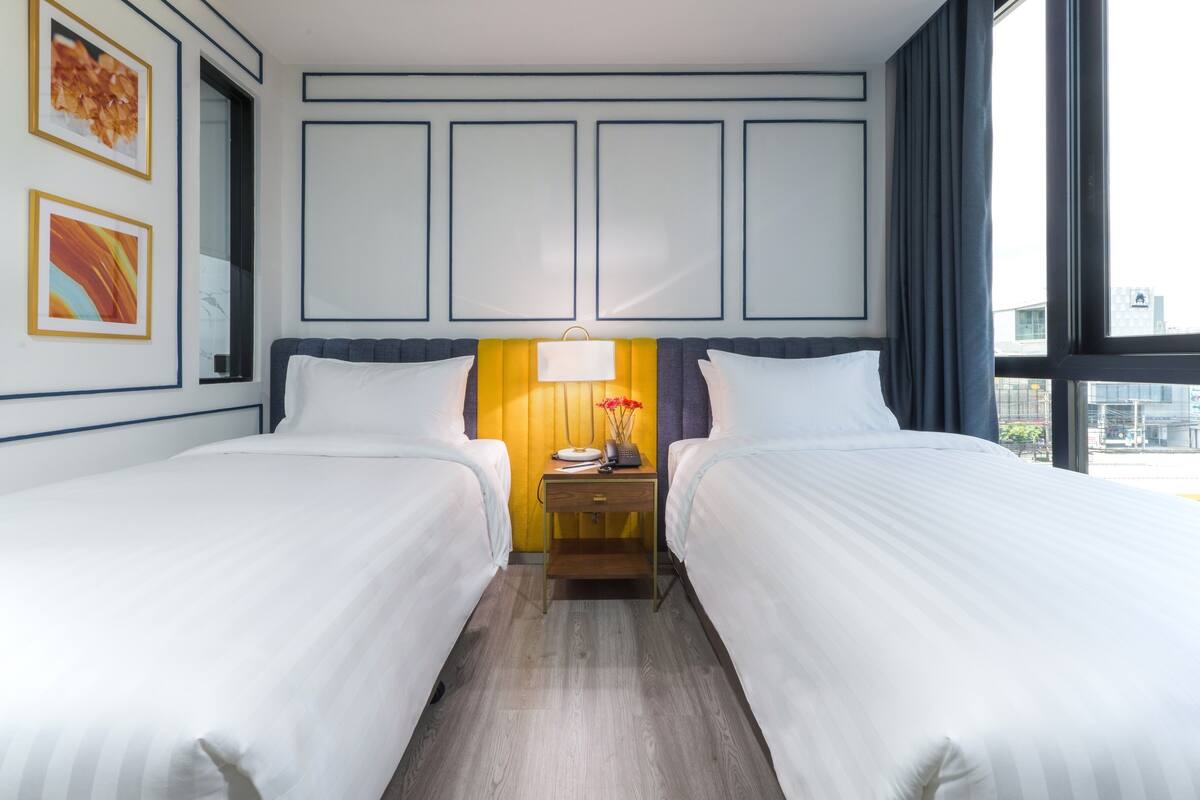 Ein Hotelzimmer mit zwei Betten, einem Nachttisch mit Lampe und einem Bild an der Wand.