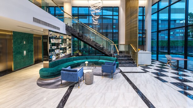 A modern lobby with a curved seating area, a staircase, and large windows. - Maven Stylish Hotel Bangkok (Bangkok)