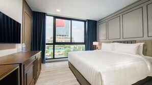 A hotel room with a large bed, a wooden dresser, a flat-screen TV, and a window with a city view. - Maven Stylish Hotel Bangkok (Bangkok)