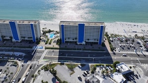 Un hotel de gran altura con varias plantas, una piscina central y una zona de playa con estacionamiento.