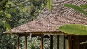A wooden balcony with a tiled roof overlooking lush greenery. - Song Broek Jungle Resort (Payangan)
