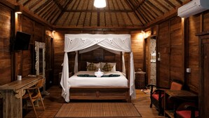 A wooden room with a four-poster bed, a flat-screen TV, and a dining table with chairs. - Song Broek Jungle Resort (Payangan)
