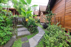 Una casa de madera con un camino de piedra que lleva a un porche rodeado de exuberante vegetación.