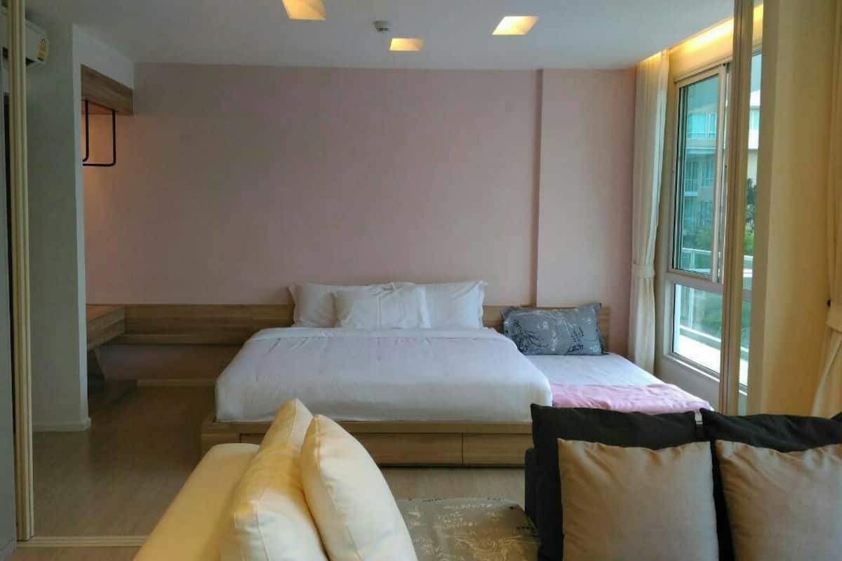 Une chambre à coucher avec un lit, des oreillers, une table de chevet et une fenêtre.