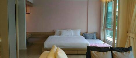A bedroom with a bed, pillows, a bedside table, and a window.
