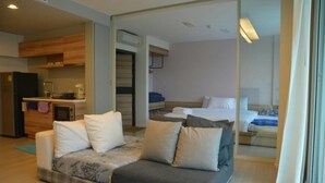 A modern hotel room with a sofa, a bed, and a kitchenette. - Luxury Wanvayla Condo (Hua Hin)