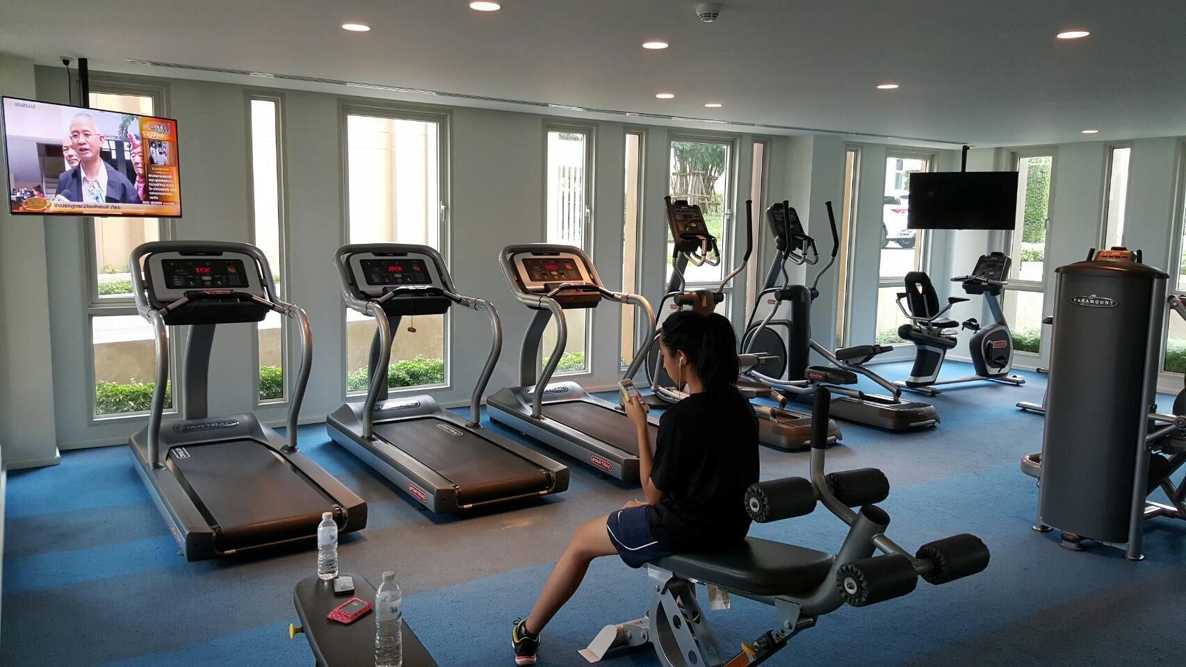 A gym with treadmills, a seated exercise machine, and a dumbbell rack.