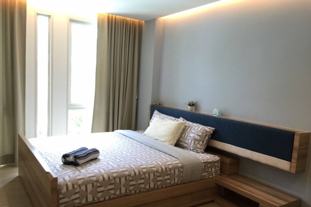 Une chambre moderne avec un grand lit, un banc intégré et une table de chevet.