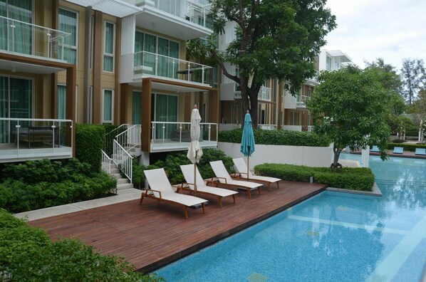 A modern hotel with a pool area, including lounge chairs and umbrellas.