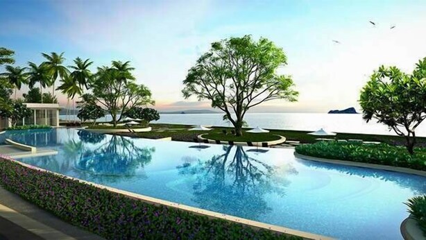 A swimming pool with a view of the sea, surrounded by palm trees and a building. - Luxury Wanvayla Condo (Hua Hin)