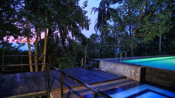 A rooftop pool with a wooden deck and a concrete edge. - The Spring Villas (Kandy)