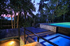 A rooftop pool with a wooden deck and a concrete edge. - The Spring Villas (Kandy)