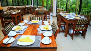 A dining area with multiple tables set for meals, surrounded by chairs with striped cushions. - The Spring Villas (Kandy)