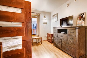 A wooden bench by a window, a dresser with drawers, a wall-mounted TV, and a sign reading "Apres-Ski Lodge".