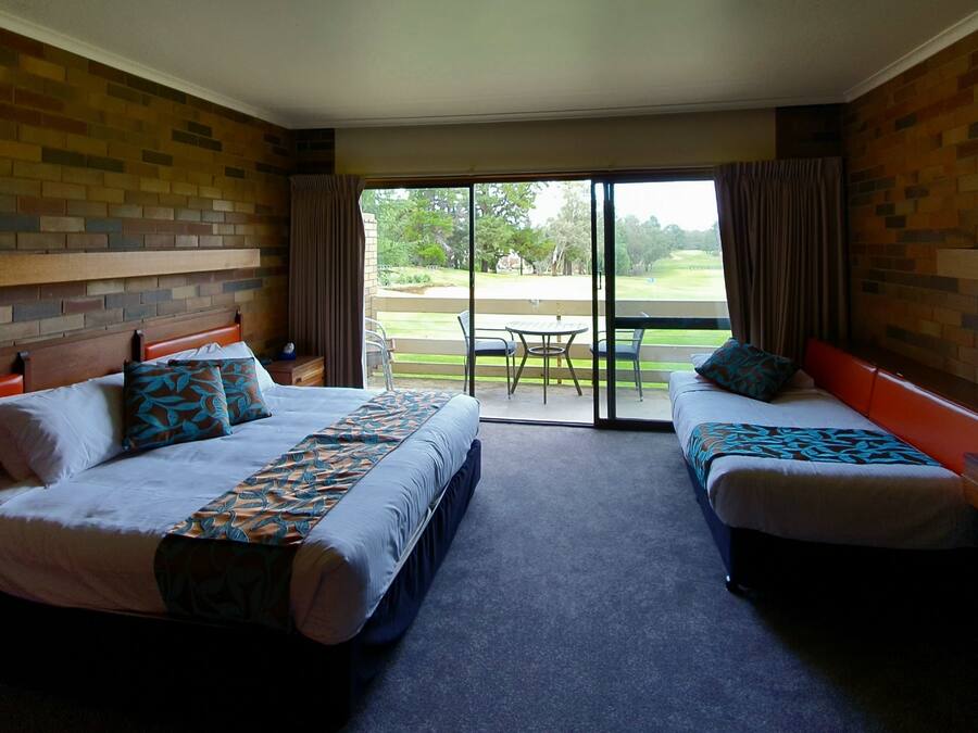 Habitación de hotel con dos camas, televisor y puerta corrediza a un patio.
