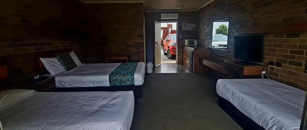 Habitación de hotel con dos camas, televisión, escritorio y vistas al exterior.
