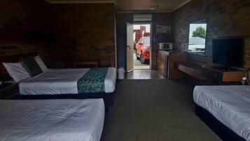 Ein Hotelzimmer mit zwei Betten, einem Fernseher, einem Schreibtisch und Blick ins Freie.