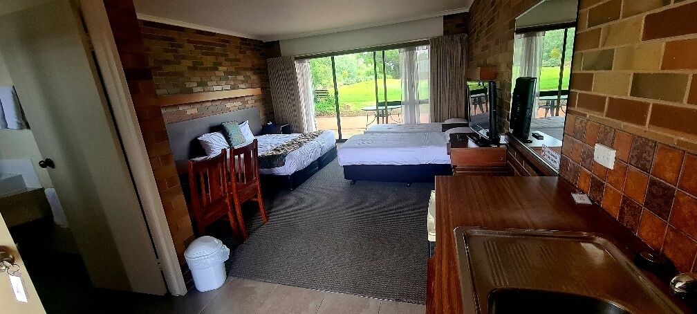 Habitación de hotel con cama, escritorio, silla, mesita, televisor y vistas al exterior.
