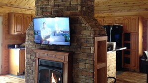 A stone fireplace with a TV mounted above it, wooden flooring, and wooden cabinets.