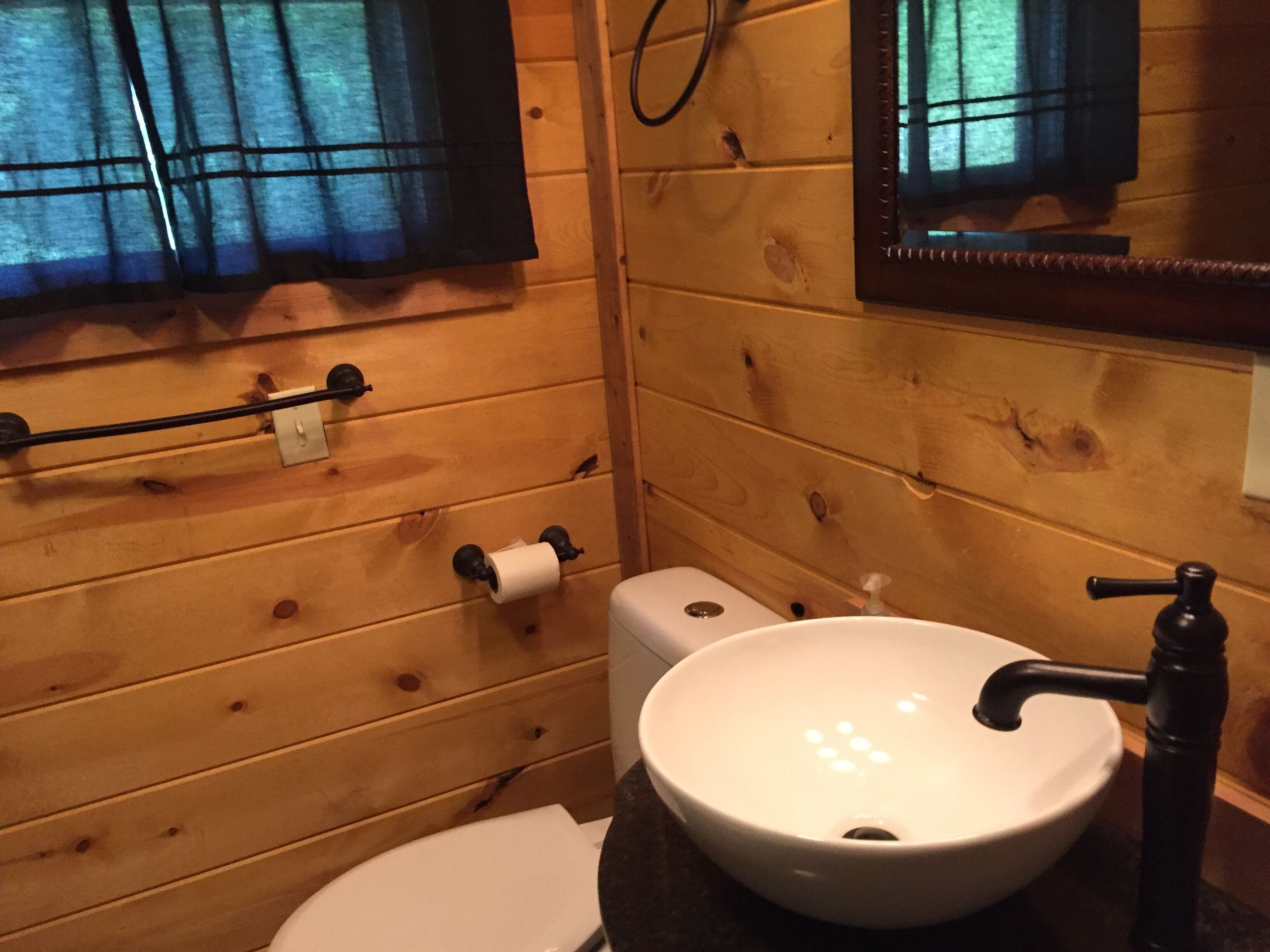 A wooden bathroom with a white sink, toilet, and towel rack.