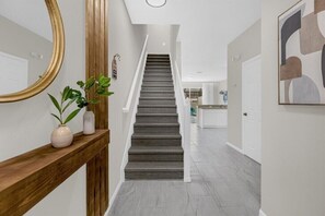 Stunning hallway with console table, mirror, and artwork, leading to a minimalist staircase.