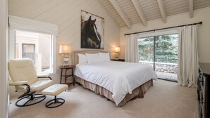 A bedroom with a large bed, a chair, a nightstand, and a window with curtains. - Book A Getaway Today! Updated Corner Condo; Close to Dollar Mountain (Sun Valley)