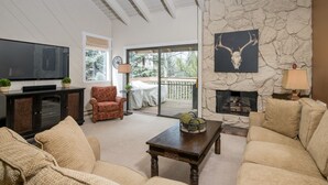 A living room with a stone fireplace, a television, and comfortable seating. - Book A Getaway Today! Updated Corner Condo; Close to Dollar Mountain (Sun Valley)