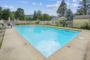A rectangular swimming pool with a concrete deck, surrounded by a white fence and trees. - Come See What Killington Does Best - Whiffletree i3 (Killington)