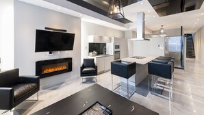 A modern living room with a flat-screen TV, a fireplace, and a dining area with bar stools.