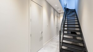 A modern interior with a metal staircase, white walls, and a tiled floor.