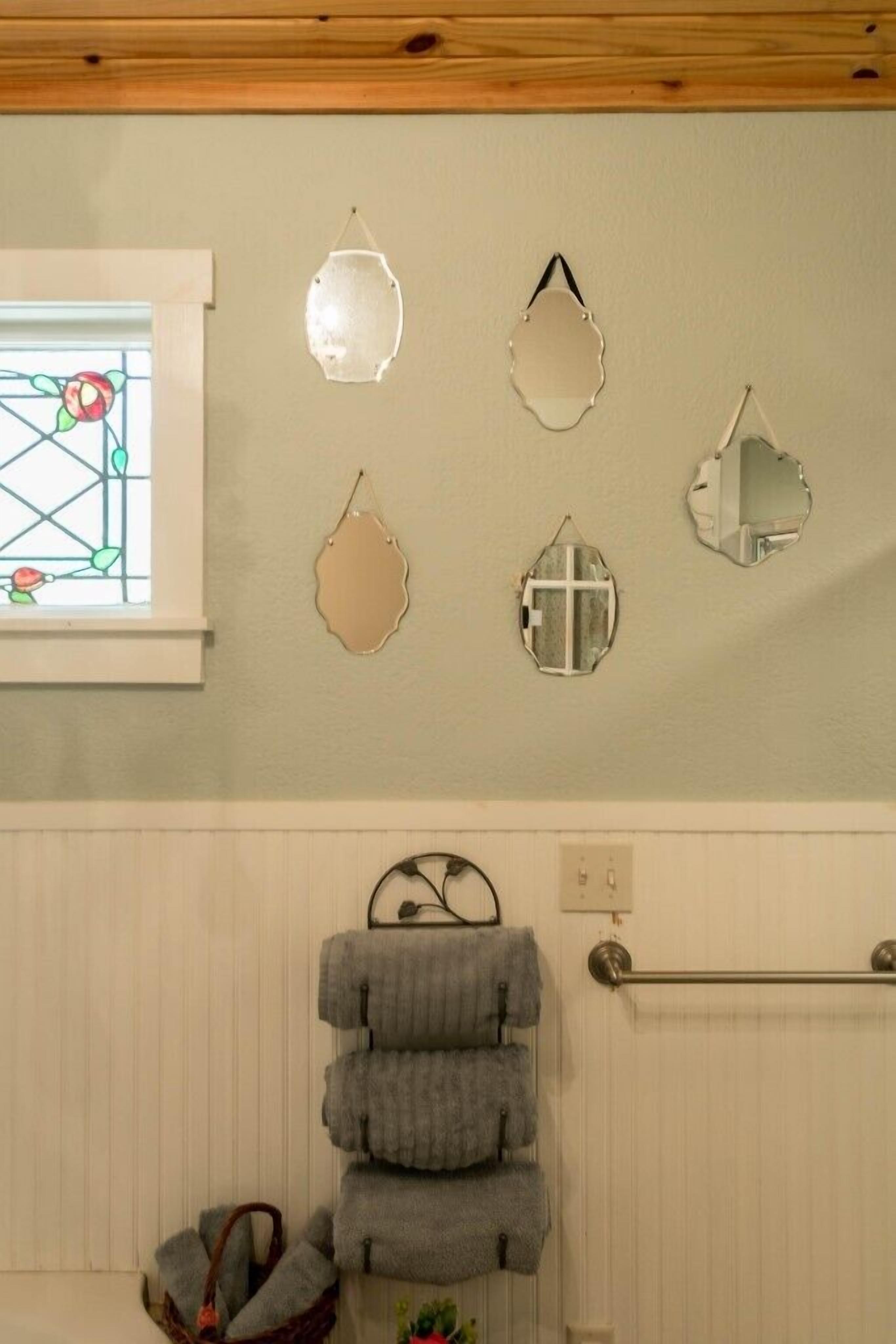 A bathroom with a window, a towel rack, and decorative mirrors on the wall.