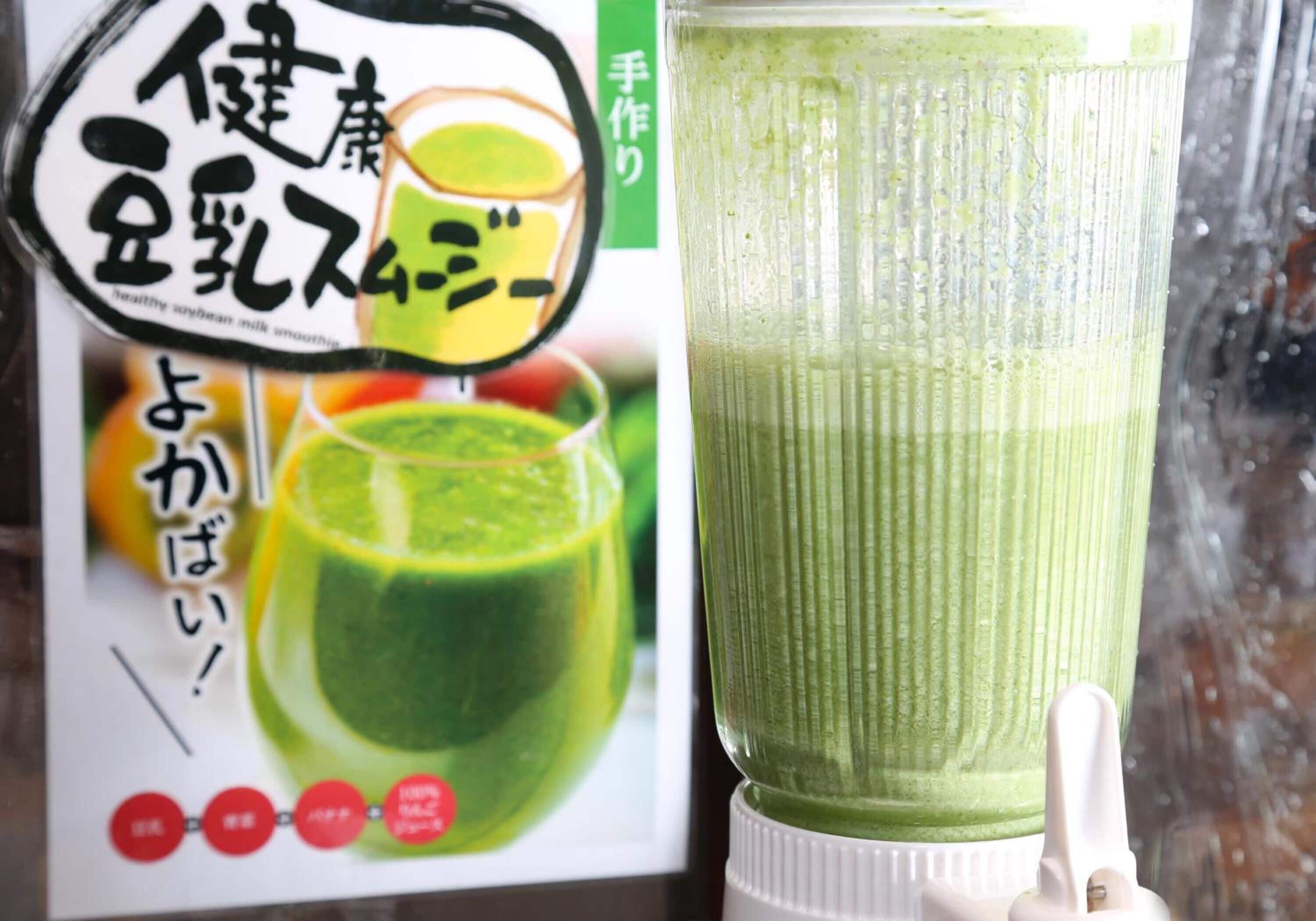 A green smoothie in a blender with a label in a foreign language.