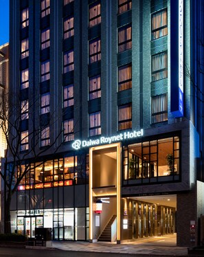 Daiwa Roynet -hotellin ulkoasu: huomiota herättävä sisäänkäynti, suuret ikkunat ja selvästi näkyvät portaat, jotka johtavat aulaan.